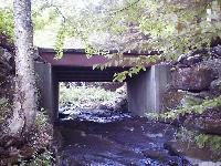 Concrete and steel bridge with wooden deck designed to handle high volumes of heavy trucks.